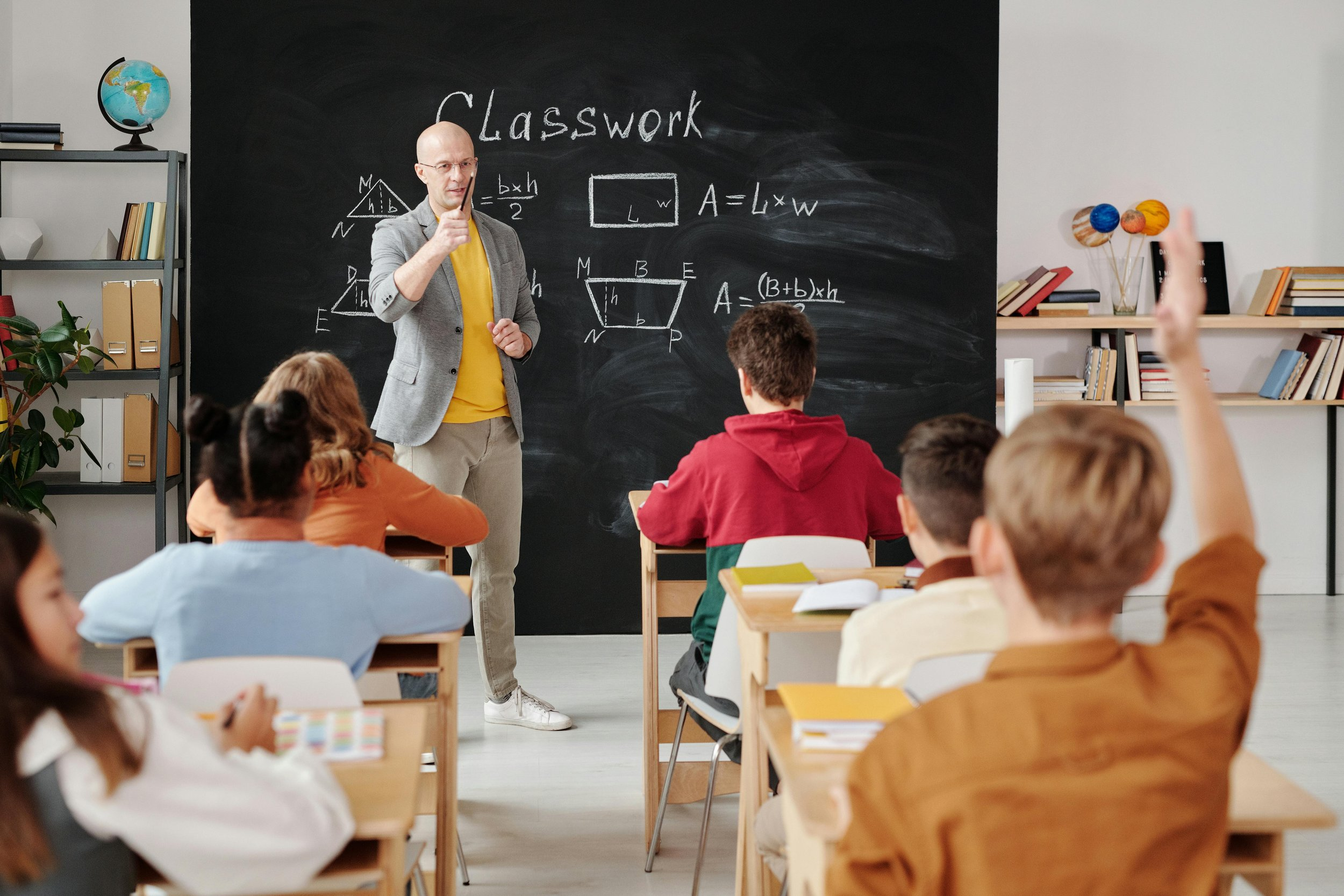 A classroom with a teacher writing on a blackboard.
